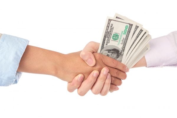 handshake exchanging dollar bills