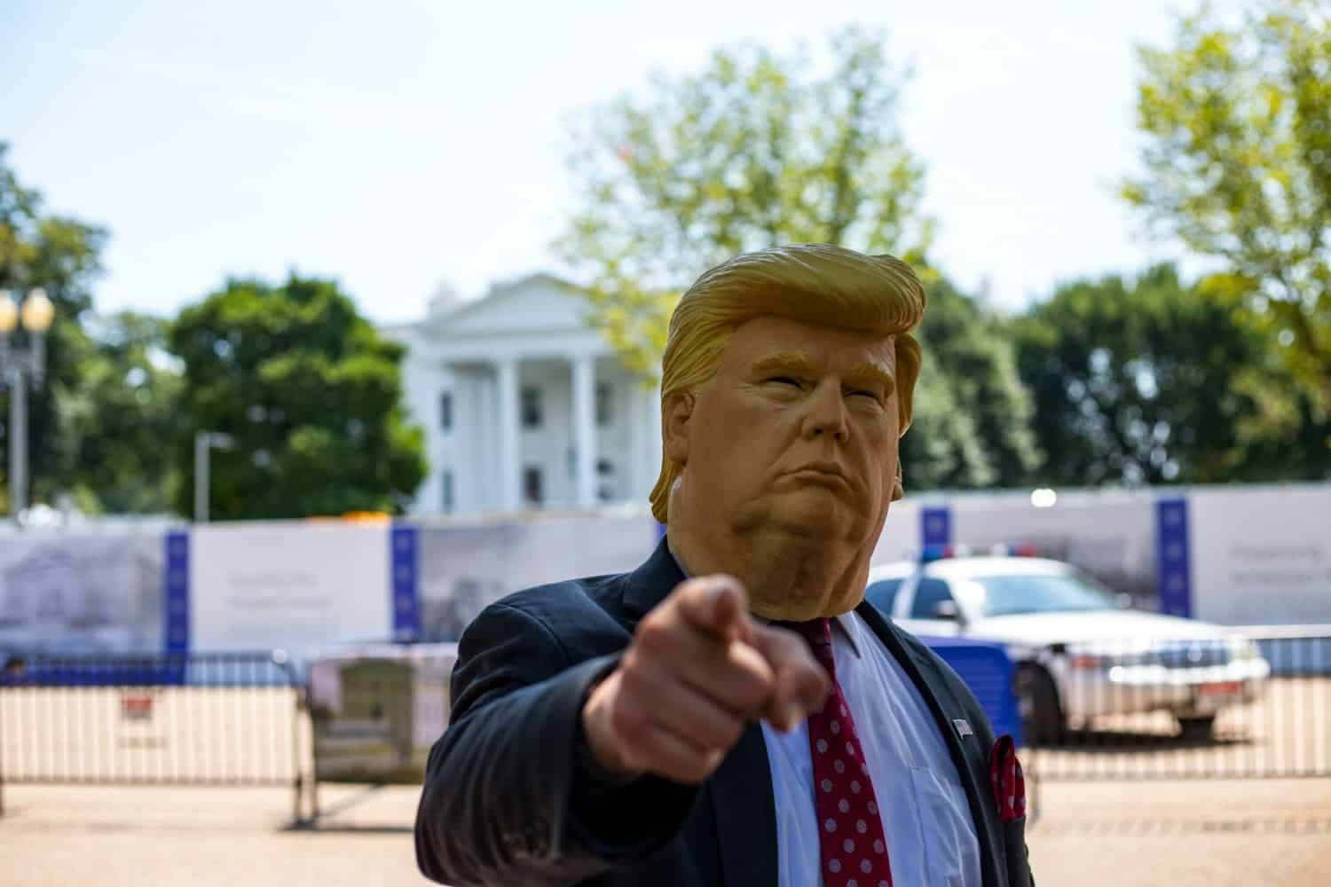 Man wearing Donald Trump mask standing in front of White House.