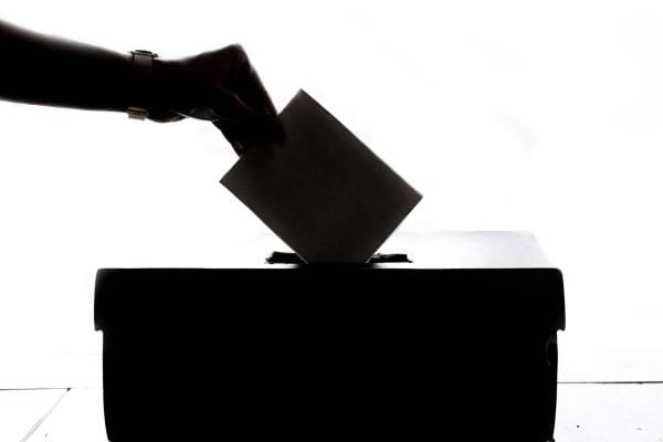 hand dropping a vote into a ballot box